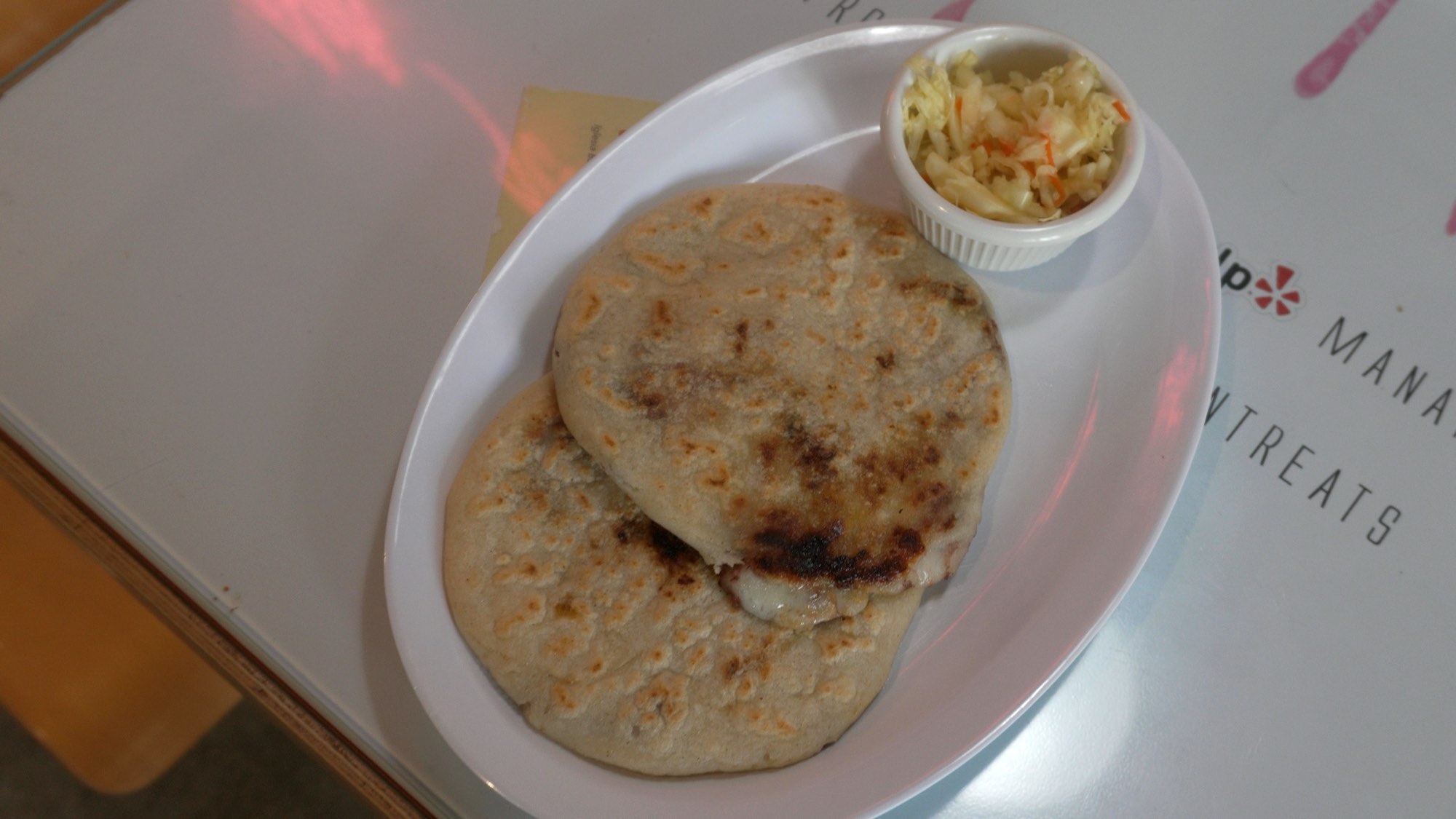 Dos pupusas con curtido en una mesa
