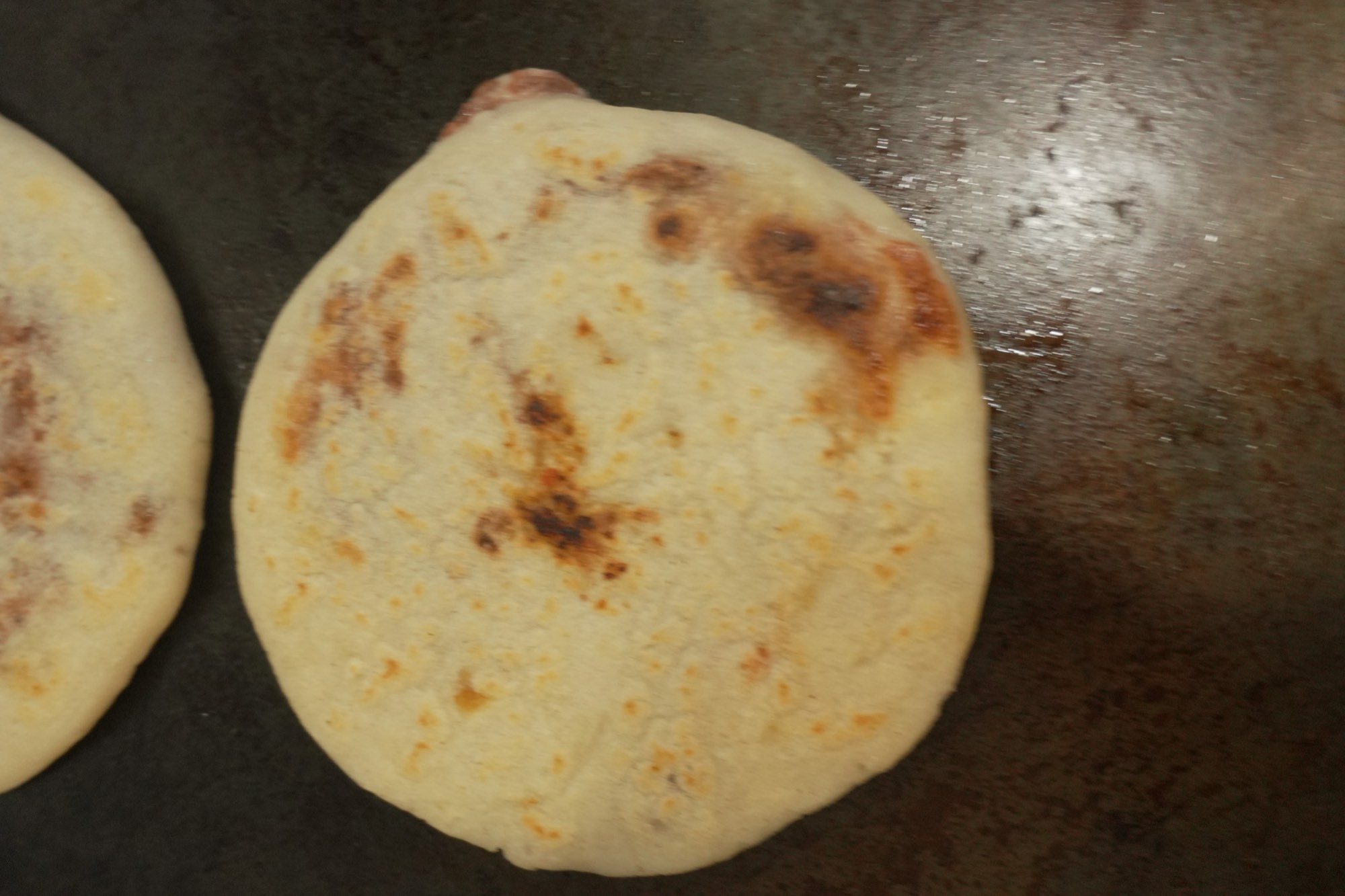Una pupusa dorada en la plancha